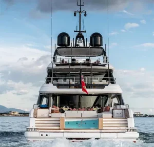 Aft view of the A+ motor yacht cruising on the water, showcasing its infinity pool and luxurious multi-level decks.