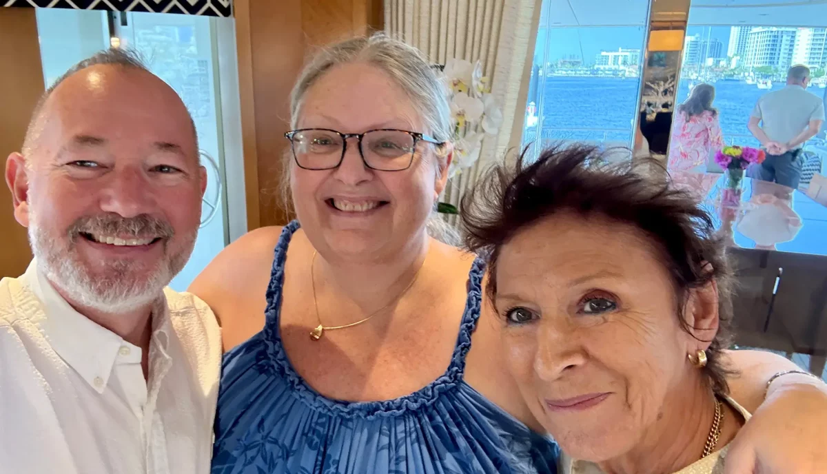 Three smiling friends posing for a selfie inside a yacht salon