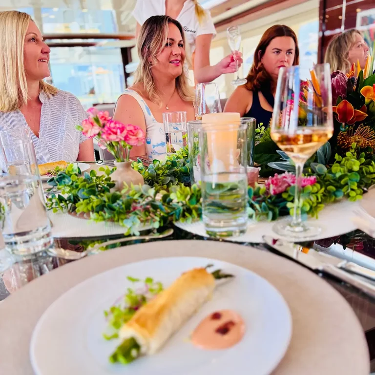 Elegant lunch setting aboard ALLORA with smiling guests and champagne